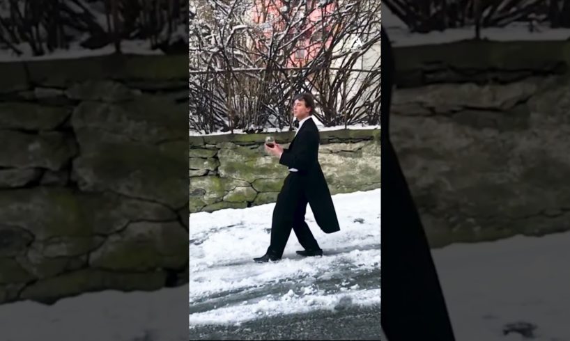 Guy Slides Down Icy Road While Wearing Suit and Holding Wine Glass in his Hand